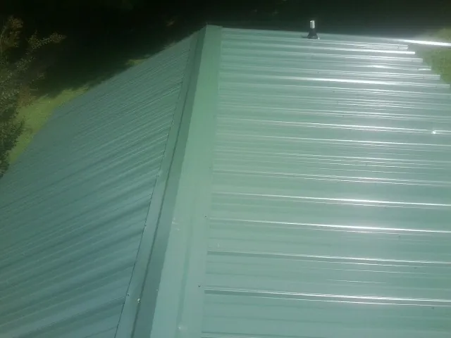 New green metal panels meeting at the ridge of a roof — Flat Roof Repair work by our crew in Andrews Air Force Base