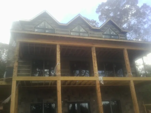 Dormers and porch framing on a large log home under construction — Roof Coating work by our crew in Andrews Air Force Base
