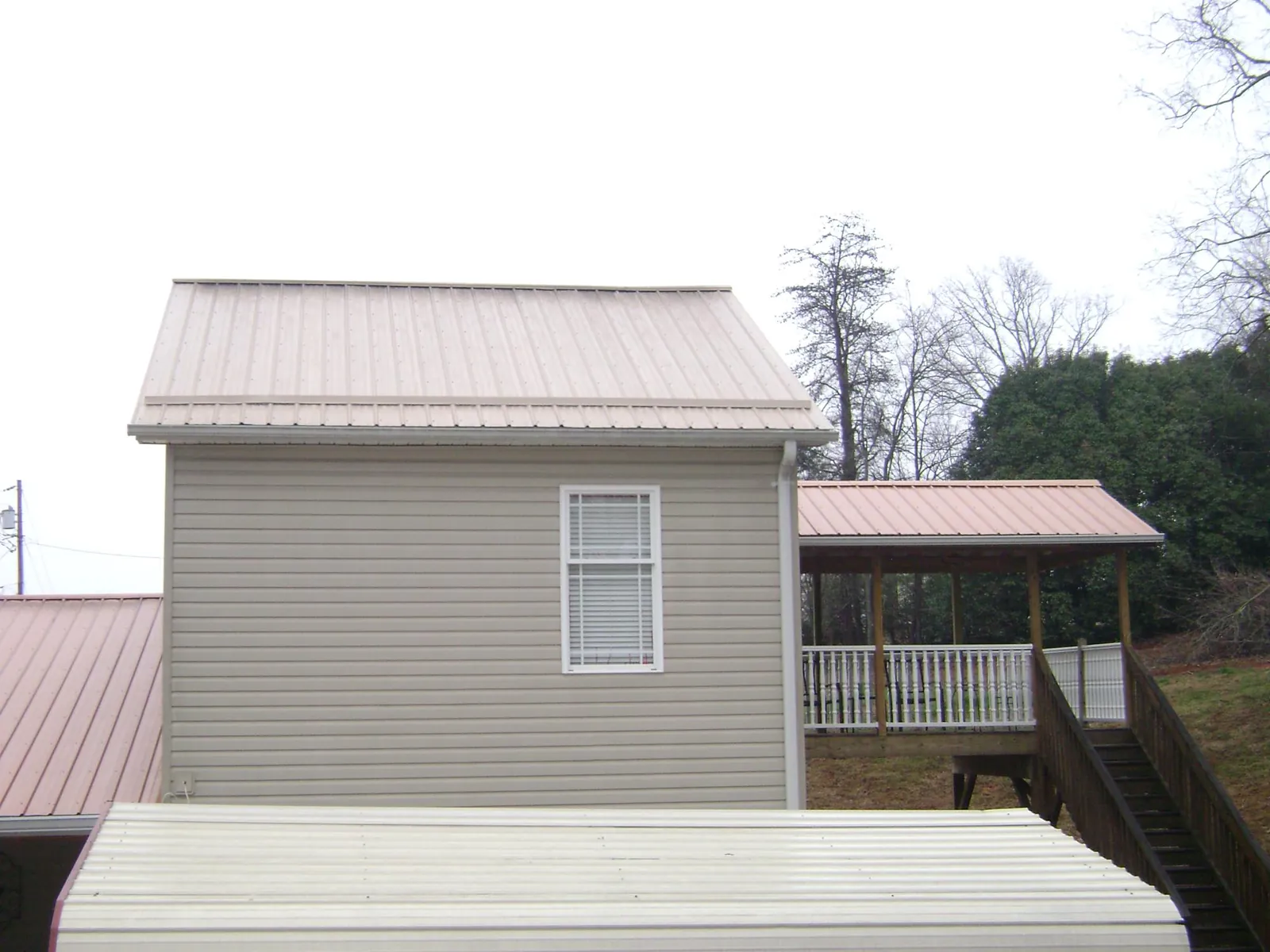 Tan metal roofs on a two story addition and attached porch, from a Roof Replacement job in Andrews Air Force Base