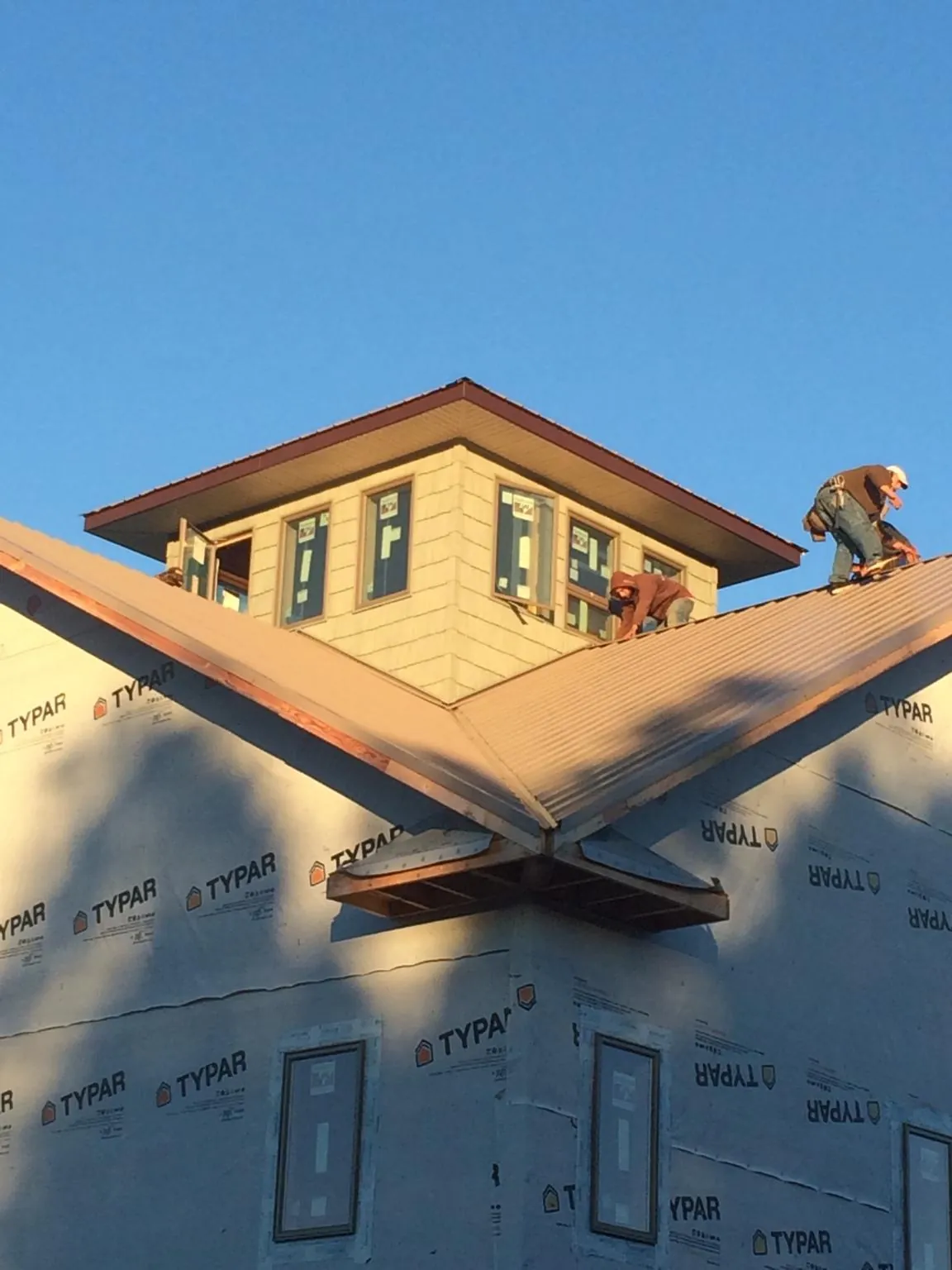 Roofers working around a rooftop cupola on a new metal roof at sunset — Roof Waterproofing in Andrews Air Force Base by Roofing Brothers